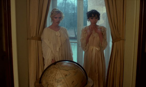 Two woman in front of a window, with a globe in front of them