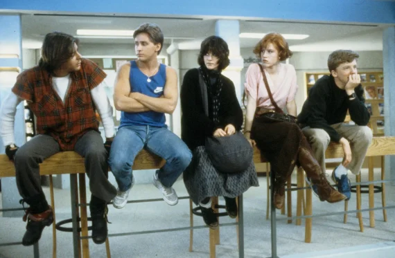 five teens are sat on a railling inside a library